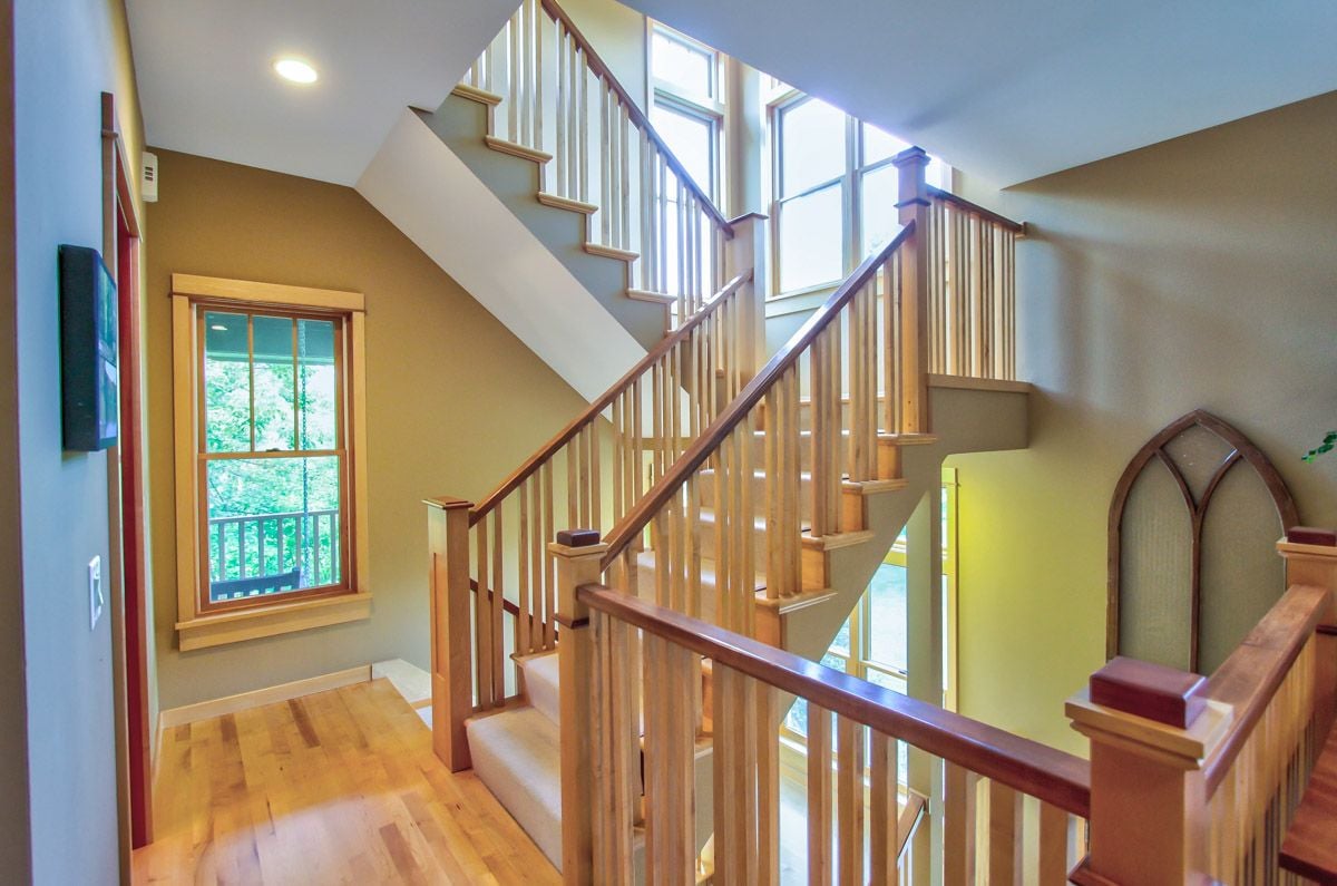 Two-story foyer with a multi-level wooden staircase, tall windows, and light wood floors.