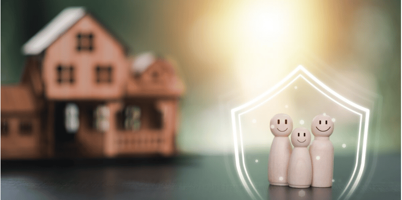 Wooden family figures inside a glowing shield, with a model house blurred behind them.