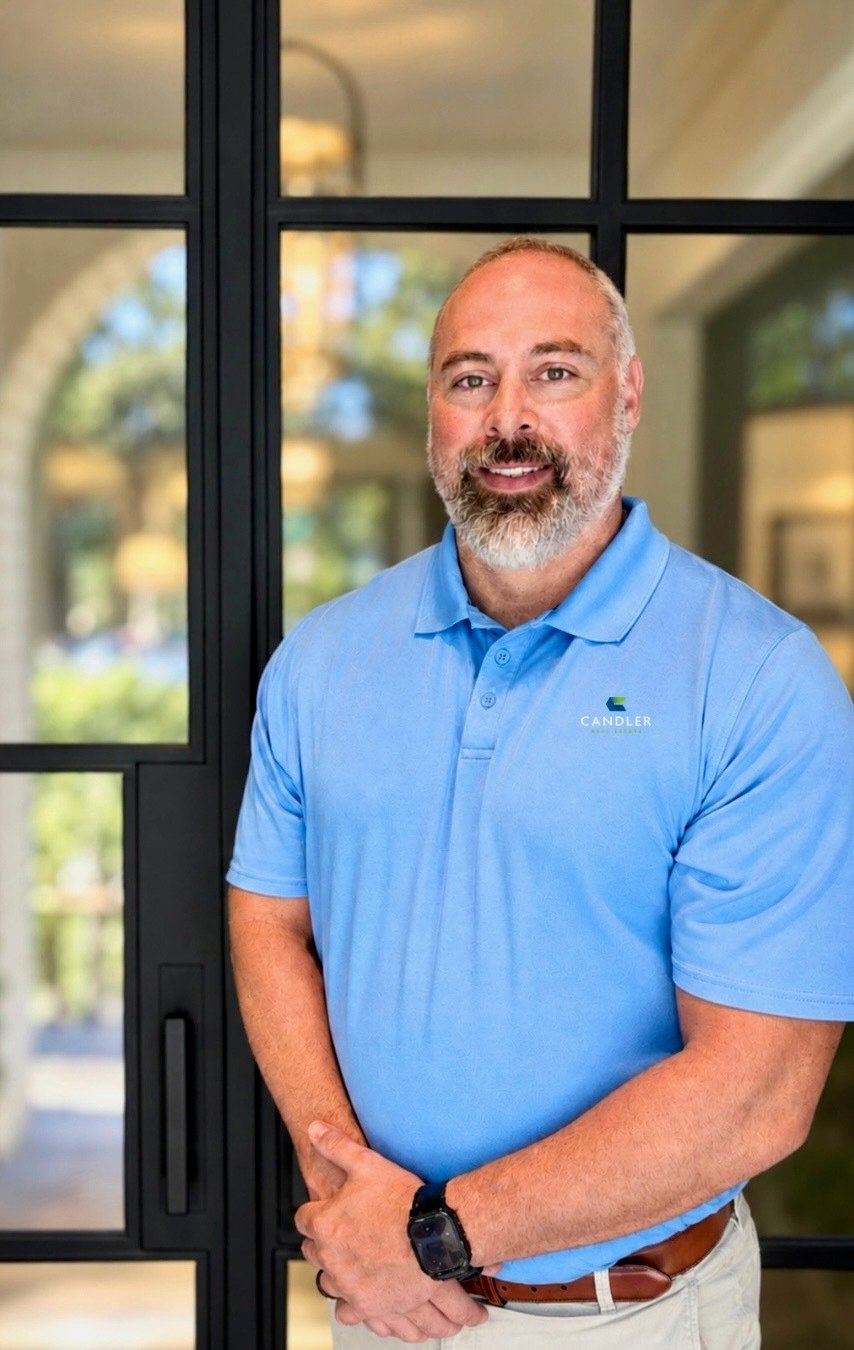 Wes Yawn in a light blue Candler polo, standing before a black-framed glass door.