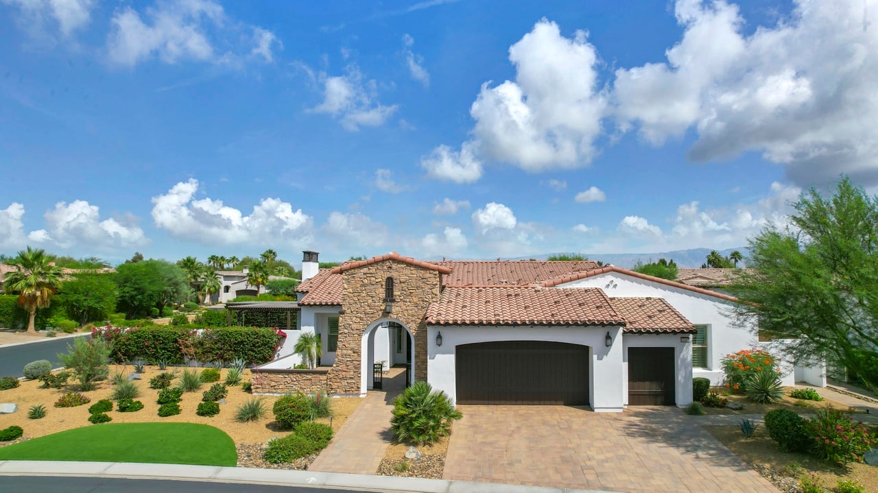 Desert home with a stone entry, terracotta tile roof, two garages, and drought-tolerant landscaping.