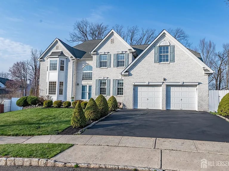 Two-story house with a gabled facade, double garage, paved driveway, and landscaped front lawn.