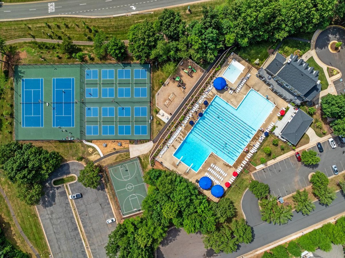 Aerial view of a community pool, tennis courts, basketball court, and clubhouse.