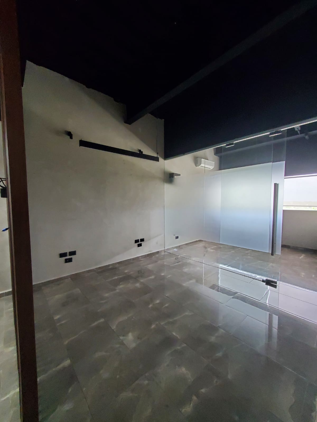 Vacant SkyCity office with glass partitions, polished gray tile floors, and a dark ceiling.