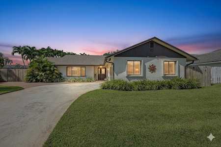 Single-story gray home with a curved driveway and broad front lawn at dusk.