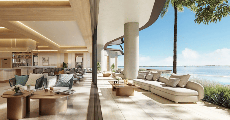 Waterfront lounge with curved cream sofas and a terrace overlooking the ocean.
