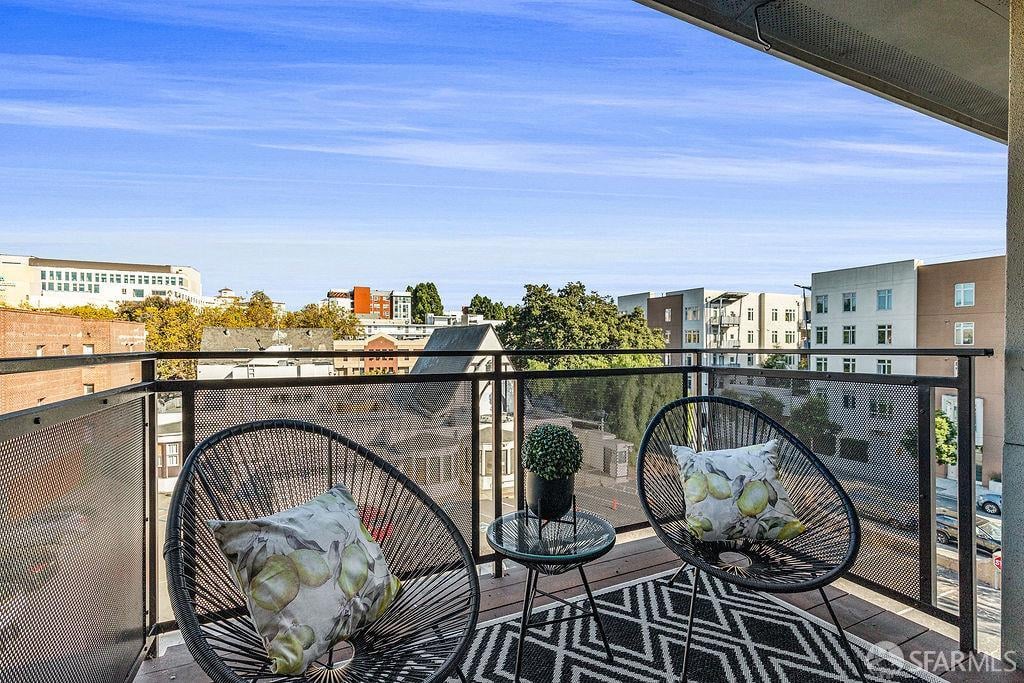 Furnished balcony with woven chairs and a city view.