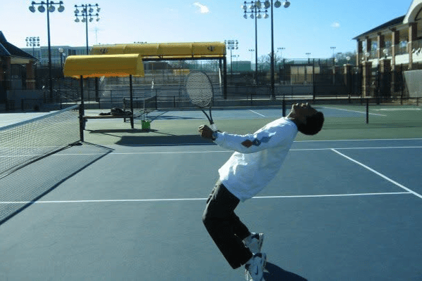 A tennis player leans back with a racket on an outdoor court.