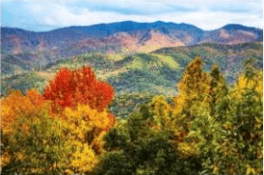Mountain ridges framed by red, yellow, and green autumn foliage.