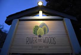 River and Woods restaurant sign illuminated against a blue evening sky.