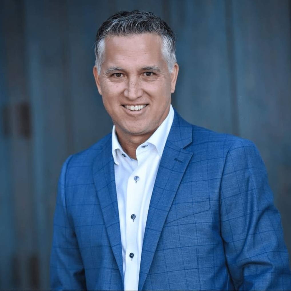 Smiling real estate agent in a blue checked suit and white shirt.