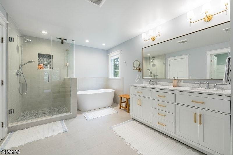 Bathroom with a glass walk-in shower, freestanding tub, and long white double-sink vanity.