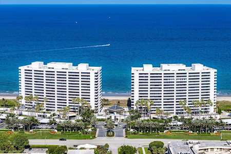 Two white beachfront condominium towers with balconies overlook the blue ocean.