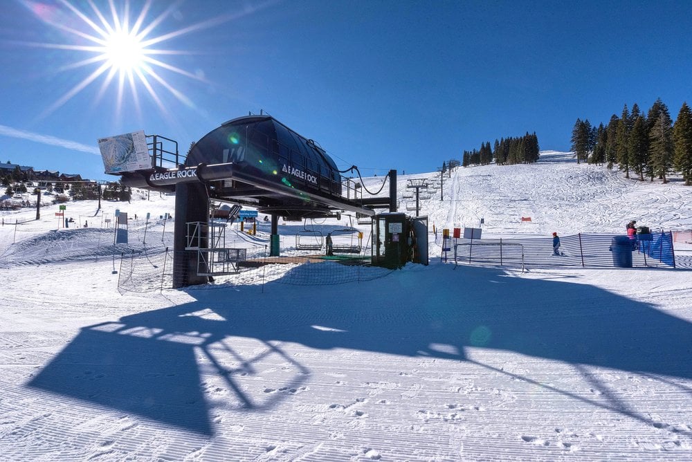 Ski lift terminal marked Eagle Rock on a sunny, snow-covered slope.