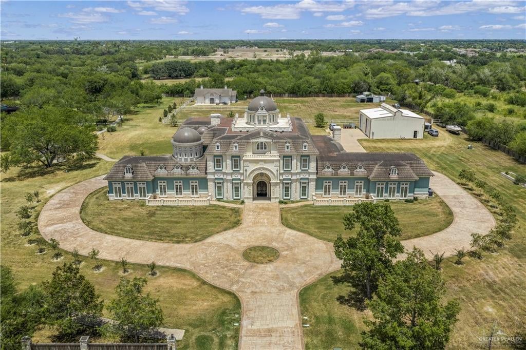 Aerial view of a large mansion with domed roofs and a circular driveway.