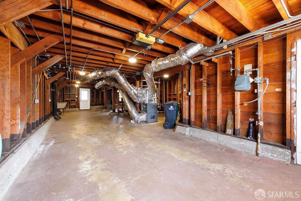 Unfinished garage with exposed wood framing, concrete floor, and prominent ductwork.