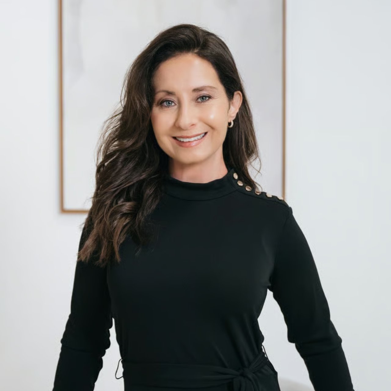 Kimberly Gilbert smiling in a black top with gold shoulder buttons.