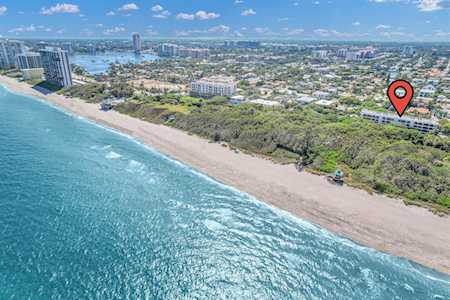 Aerial coastal neighborhood with turquoise water, a sandy beach, and a red location pin.