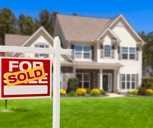 Two-story white house behind a real estate sign reading “FOR SOLD.”