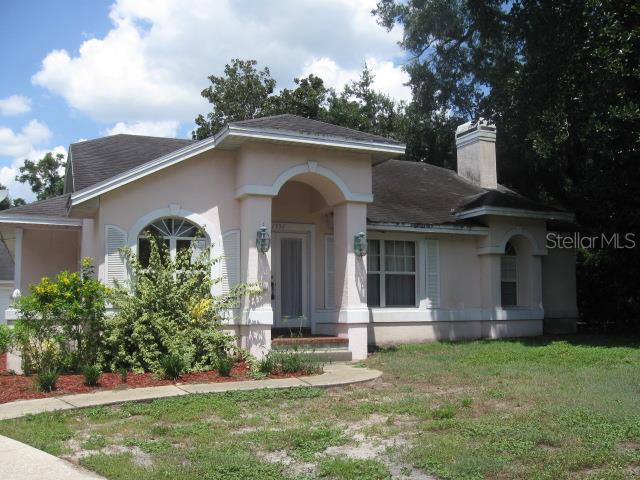Single-story pale pink stucco home with an arched entry and landscaped front yard.