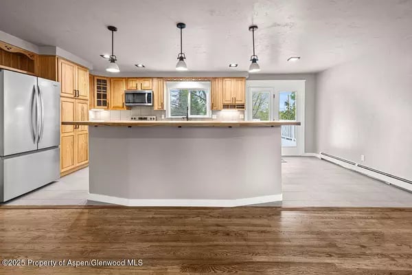 Unfurnished kitchen with light wood cabinets, stainless steel appliances, and a wide peninsula.