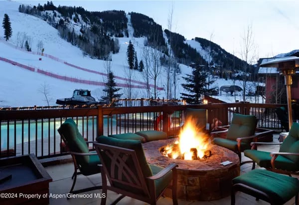 Outdoor deck with a fire pit and seating overlooking a snowy ski slope.