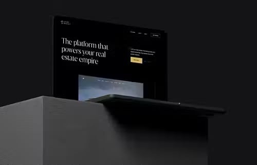 A black real estate technology website display reads “The platform that powers your real estate empire,” shown behind a dark counter.