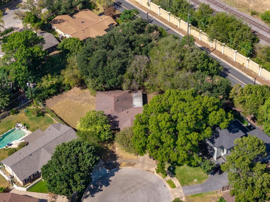 Aerial view of a tree-shaded house on a cul-de-sac beside a railway line.