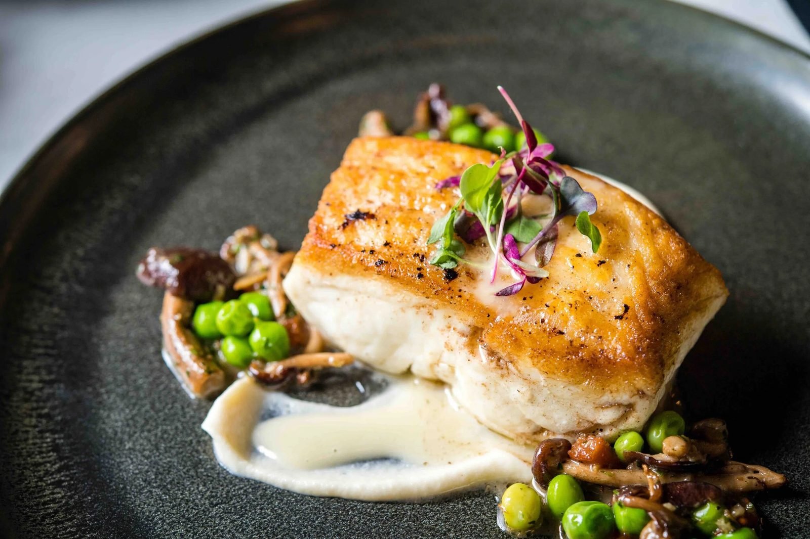 A fish dish with peas plated at Fable and Spirit.
