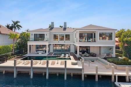 Modern waterfront home with a pool, broad patio, and dock over a canal.