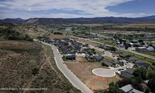 Vacant Silt lot outlined in red beside a cul-de-sac, with homes and mountains in the distance.