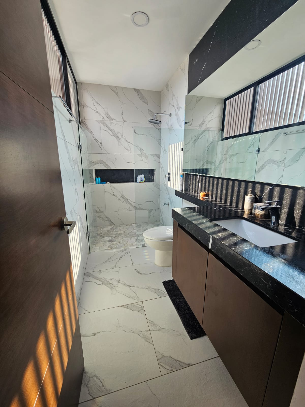 Modern bathroom with a glass walk-in shower and dark stone vanity.