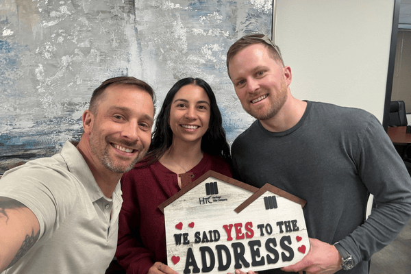 Three smiling adults hold a “We Said Yes to the Address” sign.