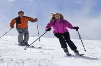 Two skiers descend a snowy slope, one in a bright pink jacket and one in orange.