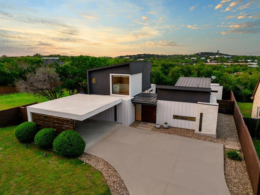 Modern home with angular white and charcoal facades, flat roofs, and a broad driveway.