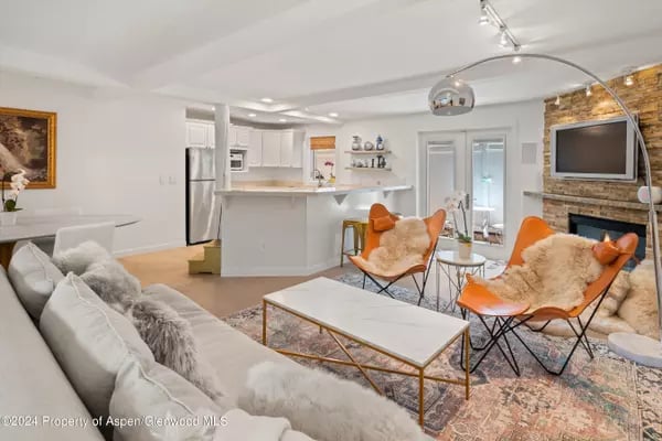 Open-plan living room with orange butterfly chairs, a white sectional, and a stone fireplace wall.