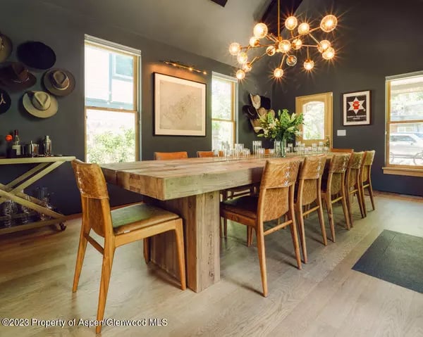 Dining room with a long rustic wood table, leather chairs, and a starburst chandelier.
