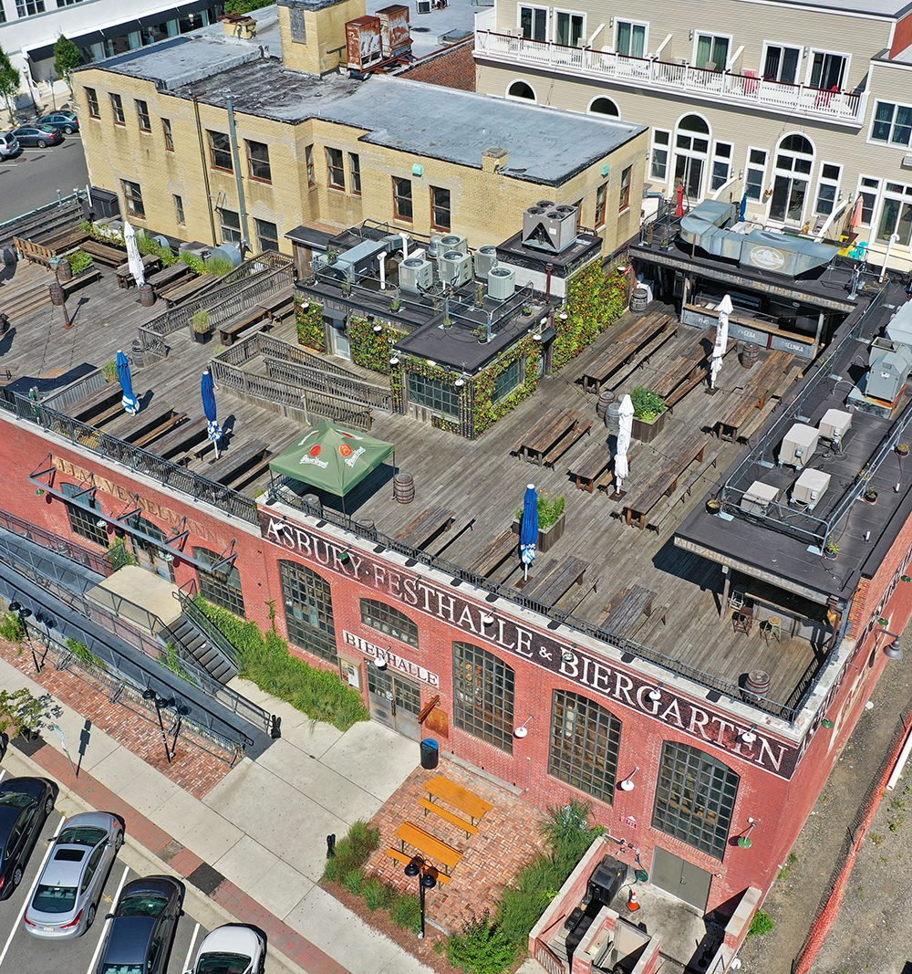 Asbury Festhalle & Biergarten with a rooftop beer garden and rows of picnic tables.