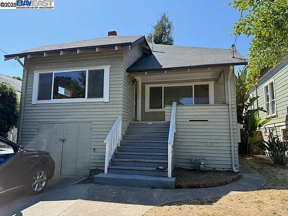 Gray-sided house with a raised porch, broad front steps, and a garage door.