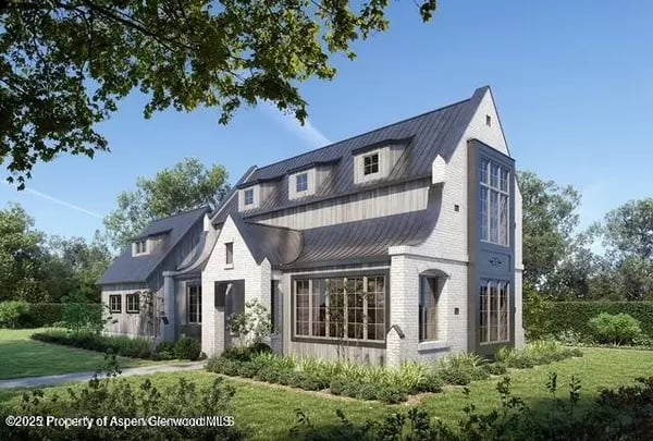 Light brick house with steep gables, a dark metal roof, and landscaped grounds.