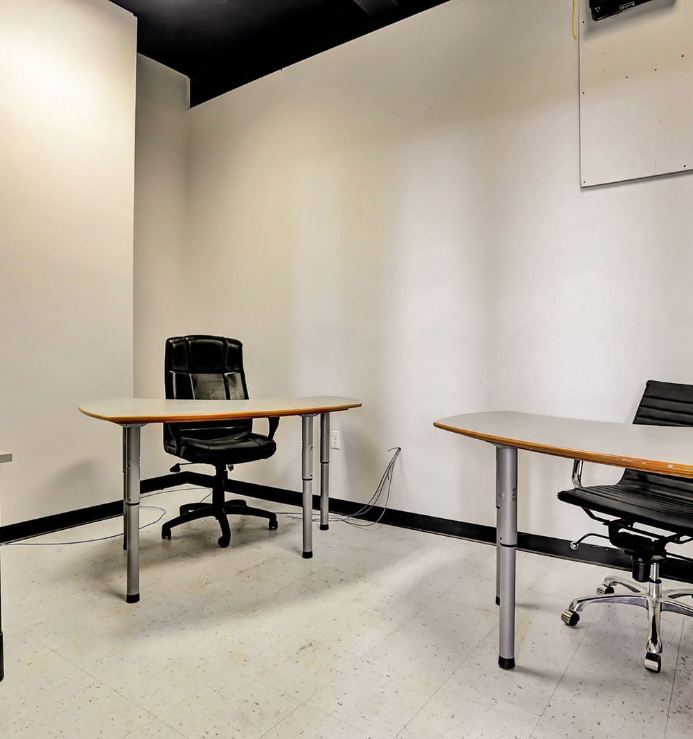 Office with two desks and black rolling chairs in a sparsely furnished room.