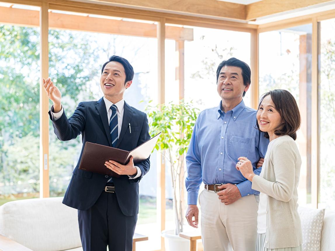 Real estate agent shows a bright, window-filled home to a smiling couple.