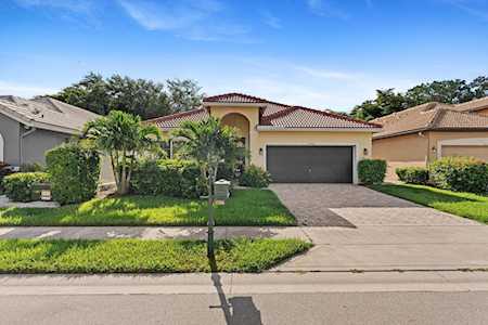 Single-story stucco home with a red tile roof, palm landscaping, and an attached two-car garage.