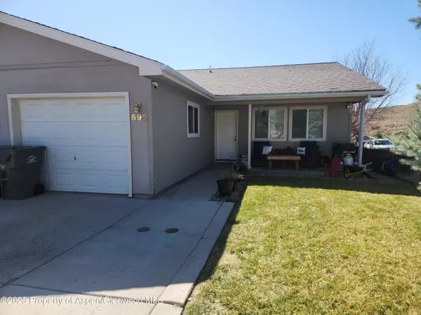 Single-story gray home with an attached garage, covered porch, and front lawn.