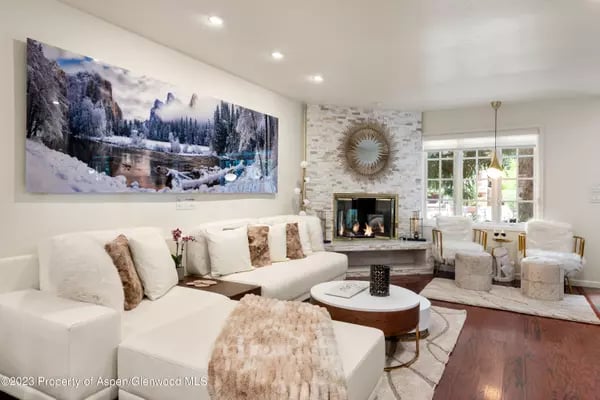 Living room with a white sectional, stone fireplace, and large windows.