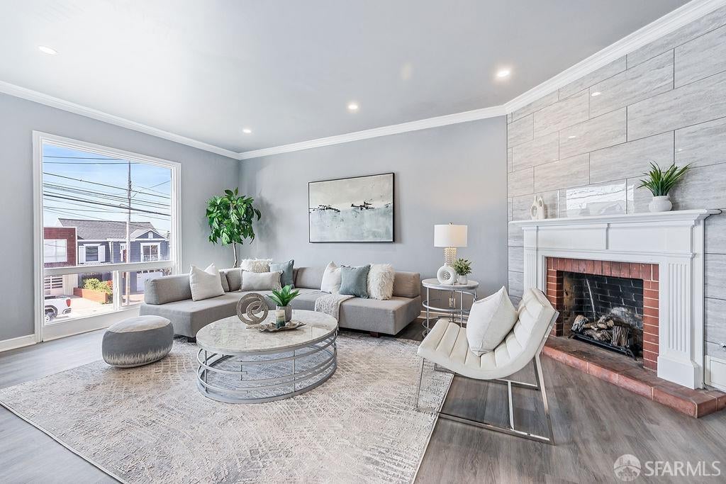 Staged living room with a gray sectional, large window, and white fireplace against a stone-tile wall.