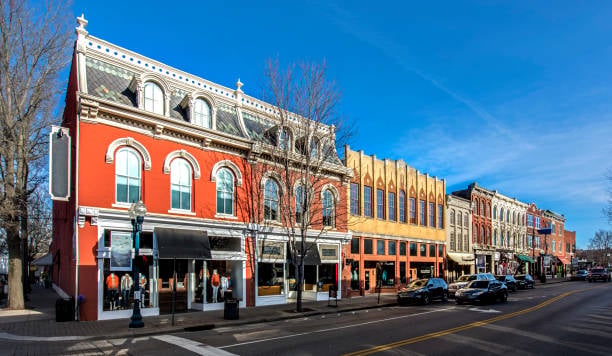 Historic downtown storefronts in colorful multistory buildings along a sunny street.