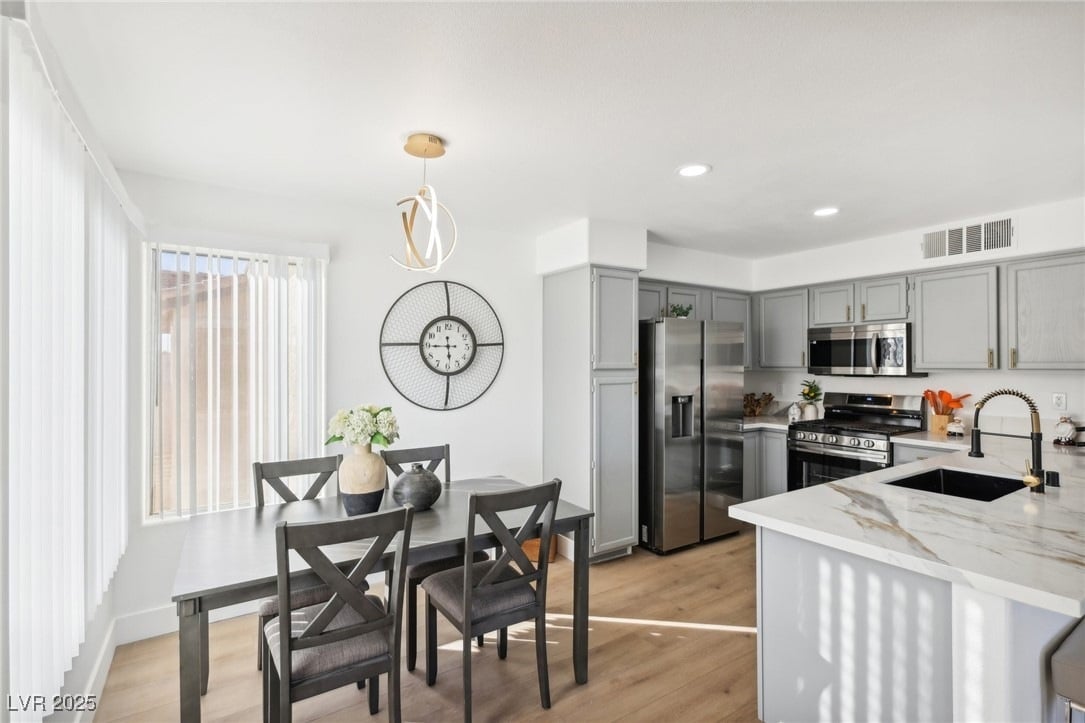 Updated Las Vegas home interior featuring a kitchen with gray cabinetry, marble-look countertops, stainless steel appliances and an adjoining dining area.