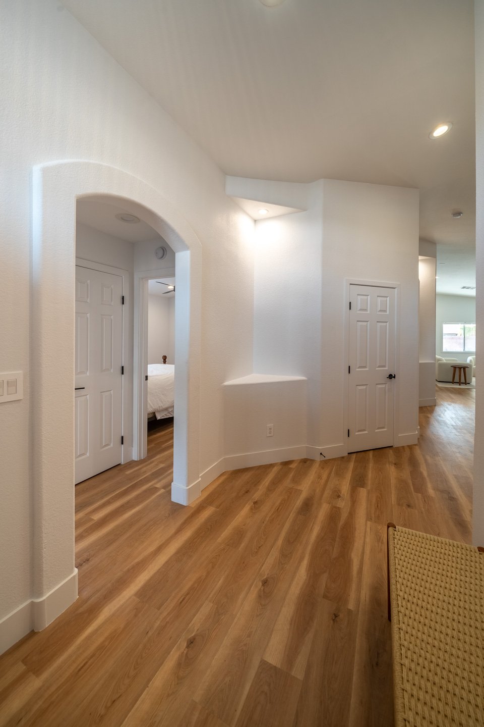 Hallway with wood floors and an arched opening to a bedroom.