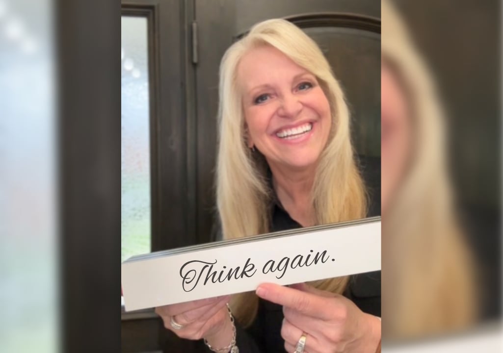 Sharla Ellis holding a “Think Again” sign, sharing insights on common housing and mortgage myths and what’s actually true in today’s market.