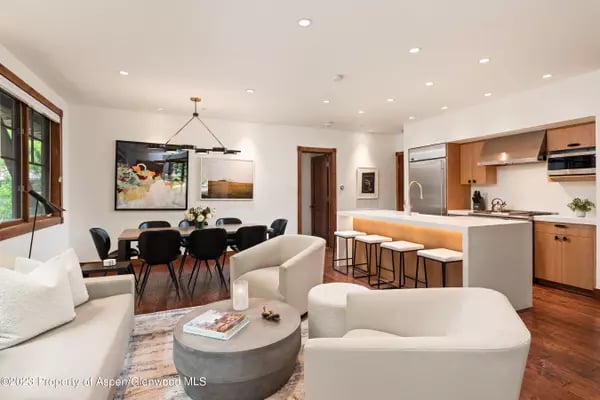 Open-plan living room, dining area, and kitchen with white sofas and a wood-cabinet breakfast bar.